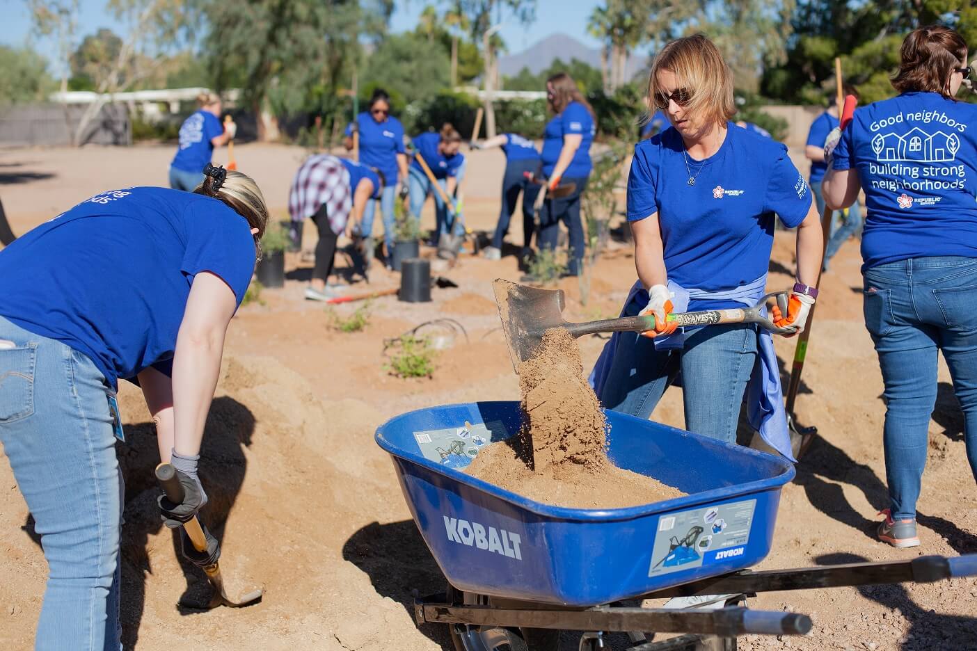 Volunteers digging in holes and transferring dirt into a wheelbarrow