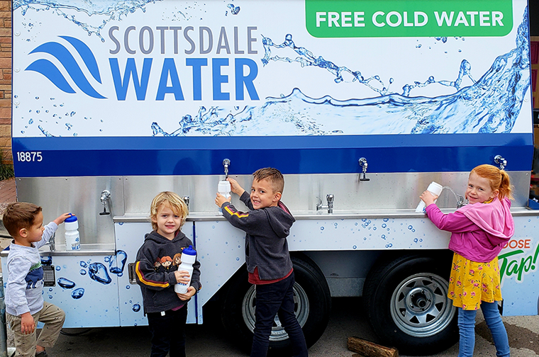4 children filling up water bottles from the scottsdale water truck