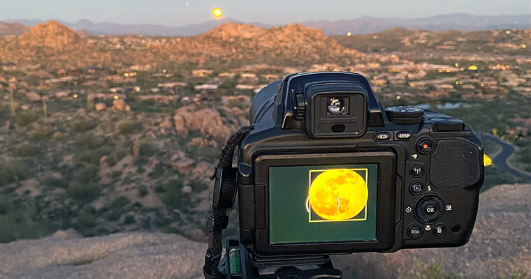 camera framing a shot of the full moon over McDowell Mountains