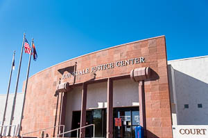 Scottsdale Justice Center entrance with stone facade, glass doors, and flags against clear sky.