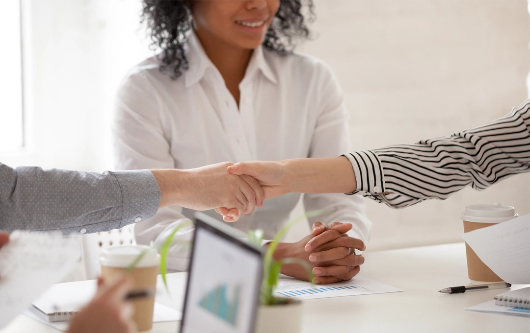 woman in between two people shaking hands