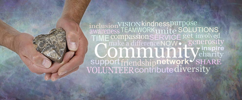 Hands cradle a heart-shaped rock inscribed with "CARE" against a textured backdrop interspersed with words like "COMMUNITY", "SERVICE", and "VOLUNTEER", evoking themes of compassion and unity.