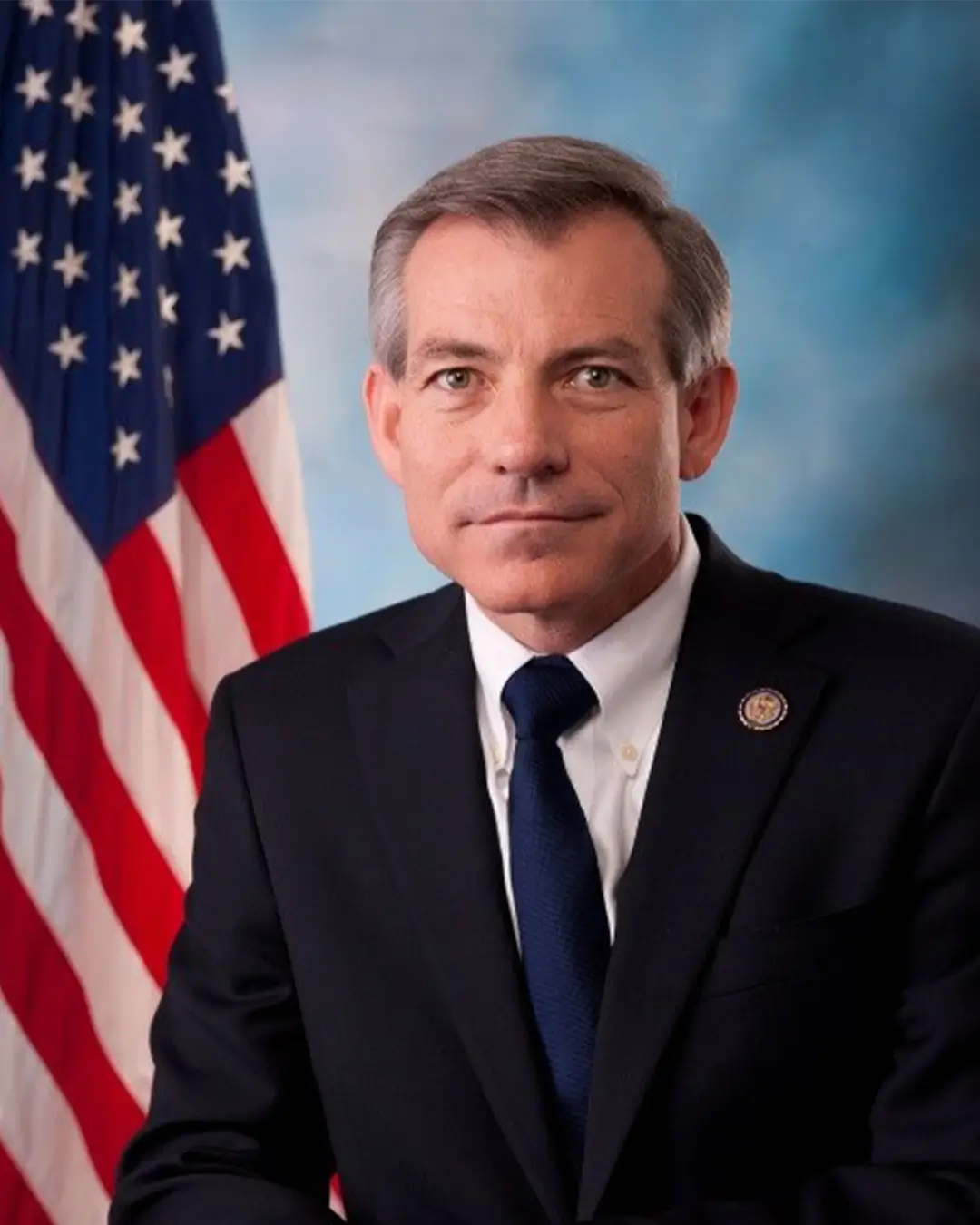 A portrait of Congressman David Schweikert standing in front of an American flag.