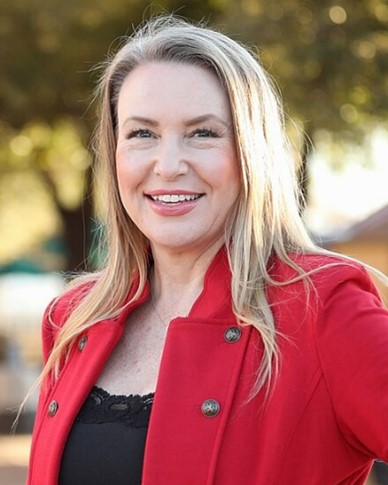 An outdoor portrait of Senator Carine Werner smiling in front of a tree.