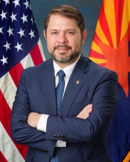 A portrait of Senator Ruben Gallego in front of an American and Arizonan flag.