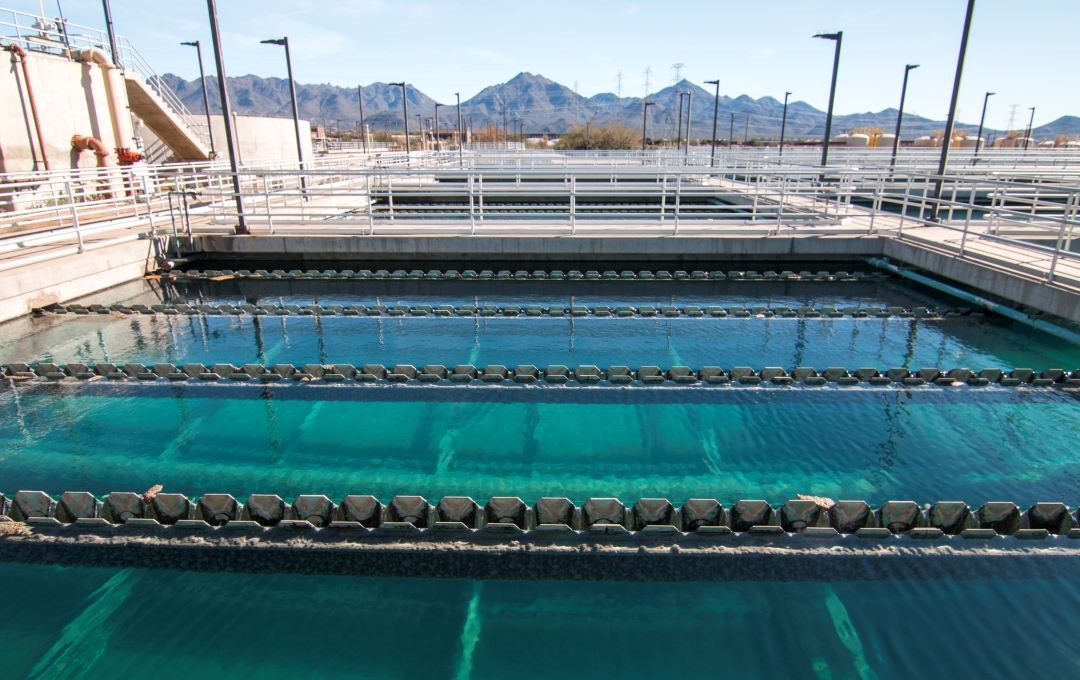 Clear blue water treatment basins at a facility with mountains in the background.