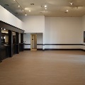 An empty event room with a dark wood bar along one wall, track lighting, a desert landscape painting and glass doors to the patio.