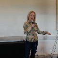 A speaker in a patterned western shirt talks into a microphone next to a speaker on a stand.