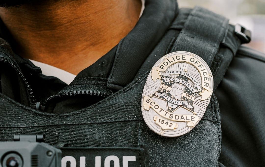 Close-up of a Scottsdale police officer badge on a black tactical vest.