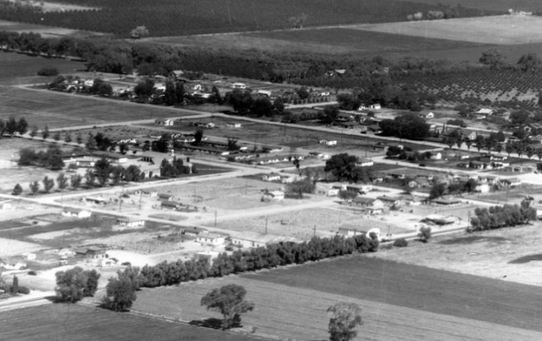 Aerial black-and-white view of early town development surrounded by farmland and scattered homes.