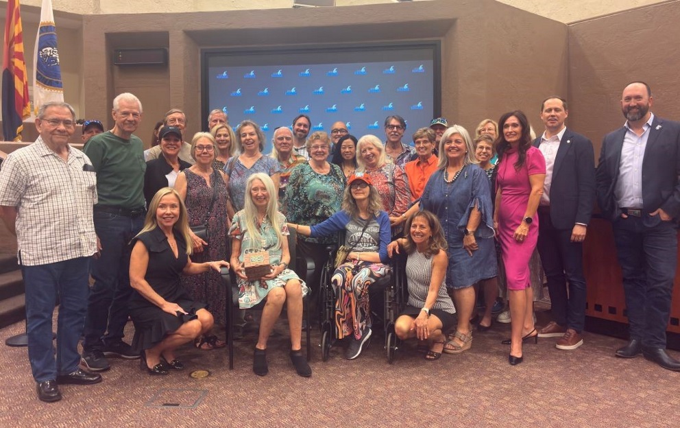 A large group of diverse individuals poses for a group photograph in an indoor formal setting.