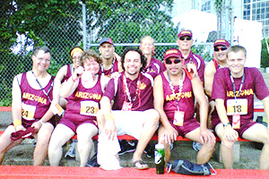 Group of athletes in matching maroon “Arizona” jerseys smiling together on outdoor bleachers.