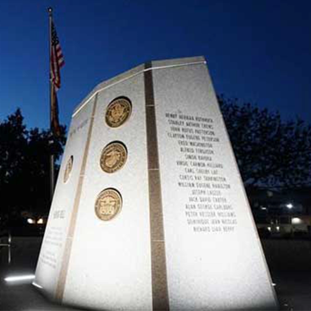 Illuminatedmilitarymemorialmonumentwithserviceemblemsandengravednamesatdusk