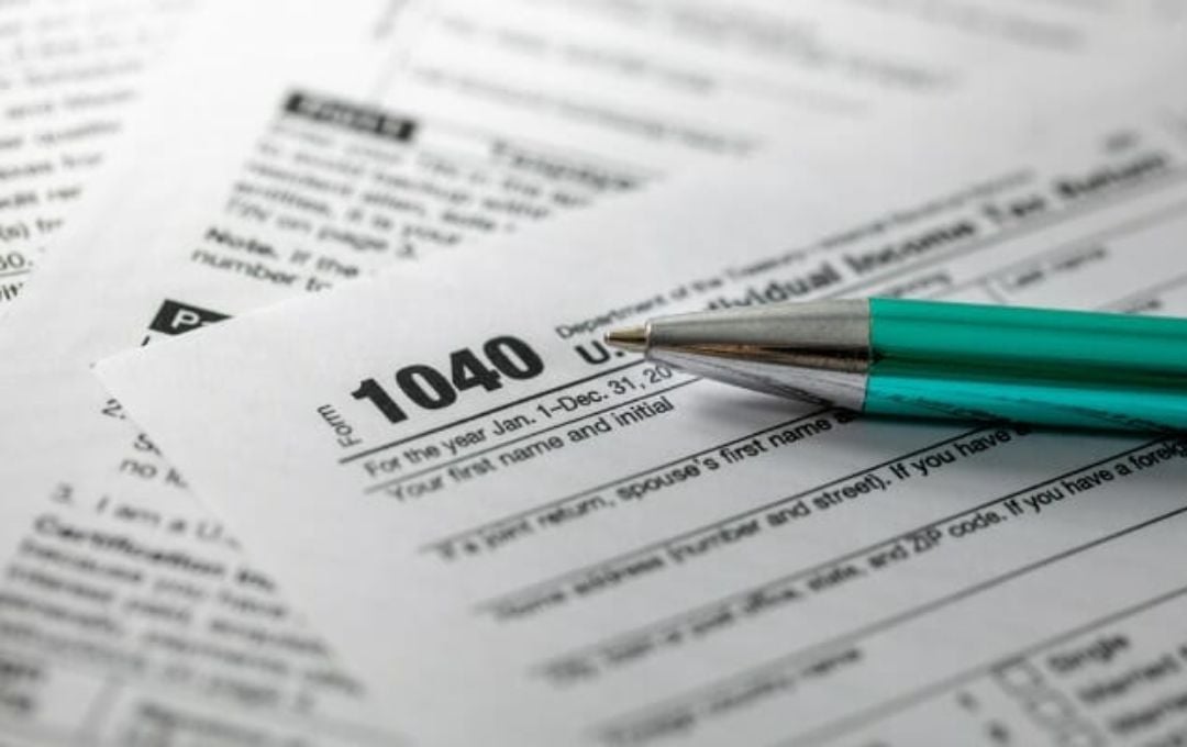 Eyeglasses and a pen resting on a printed form atop a computer keyboard.